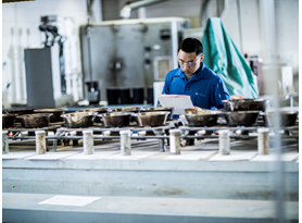 Man in laboratory examining soil boring samples in a row of metal containers