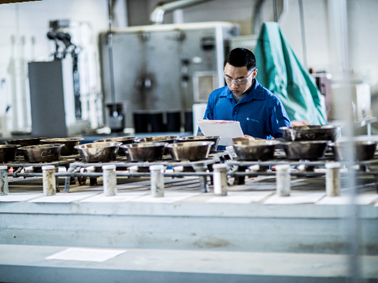 Man in laboratory examining soil boring samples in a row of metal containers